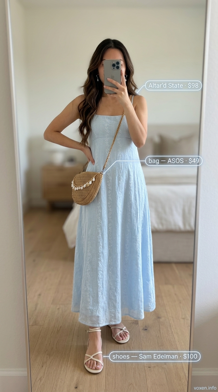 Boho summer flowy maxi dress 2026 in sky blue. Beach wedding guest outfit with raffia bag and silver earrings.