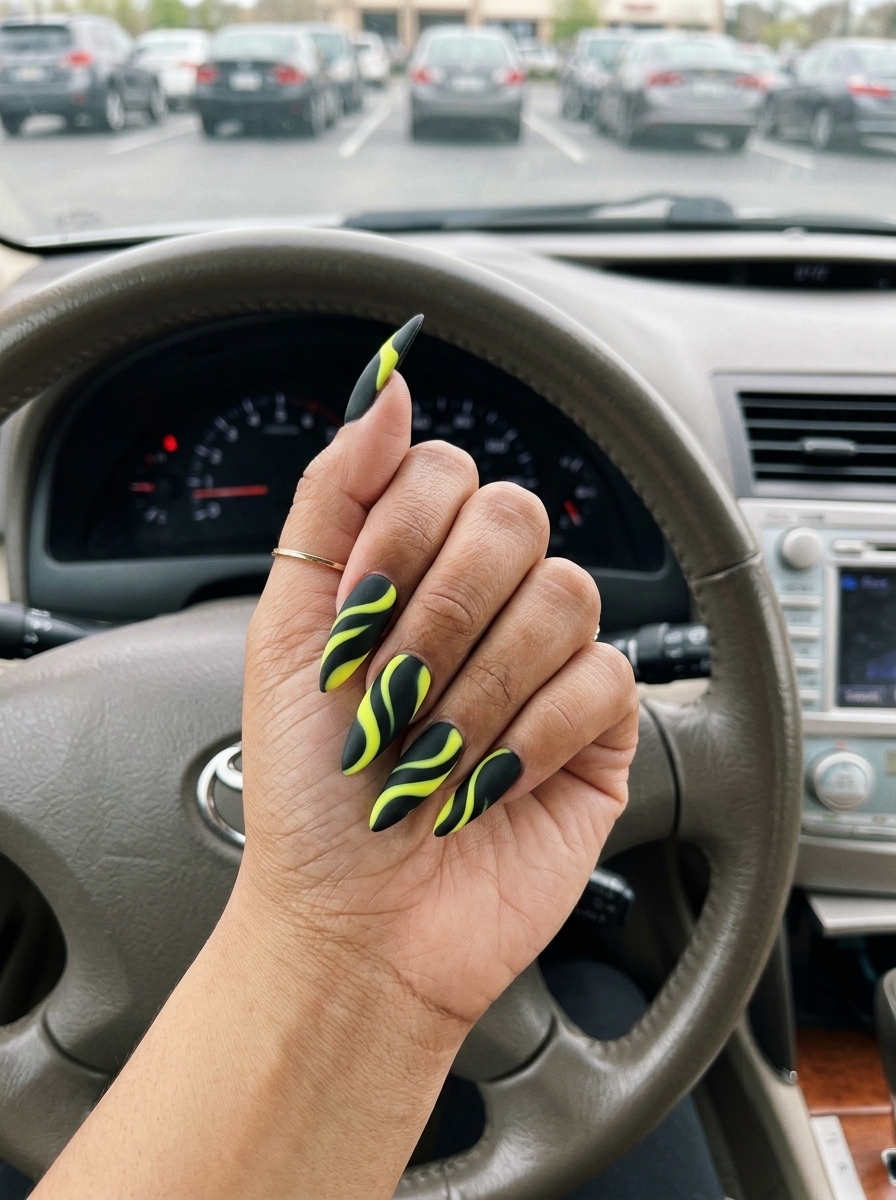 Neon Yellow Swirls 2026 | Edgy Festival Neon yellow abstract swirls on matte black coffin nails for summer nails yellow 2026. Edgy festival look.