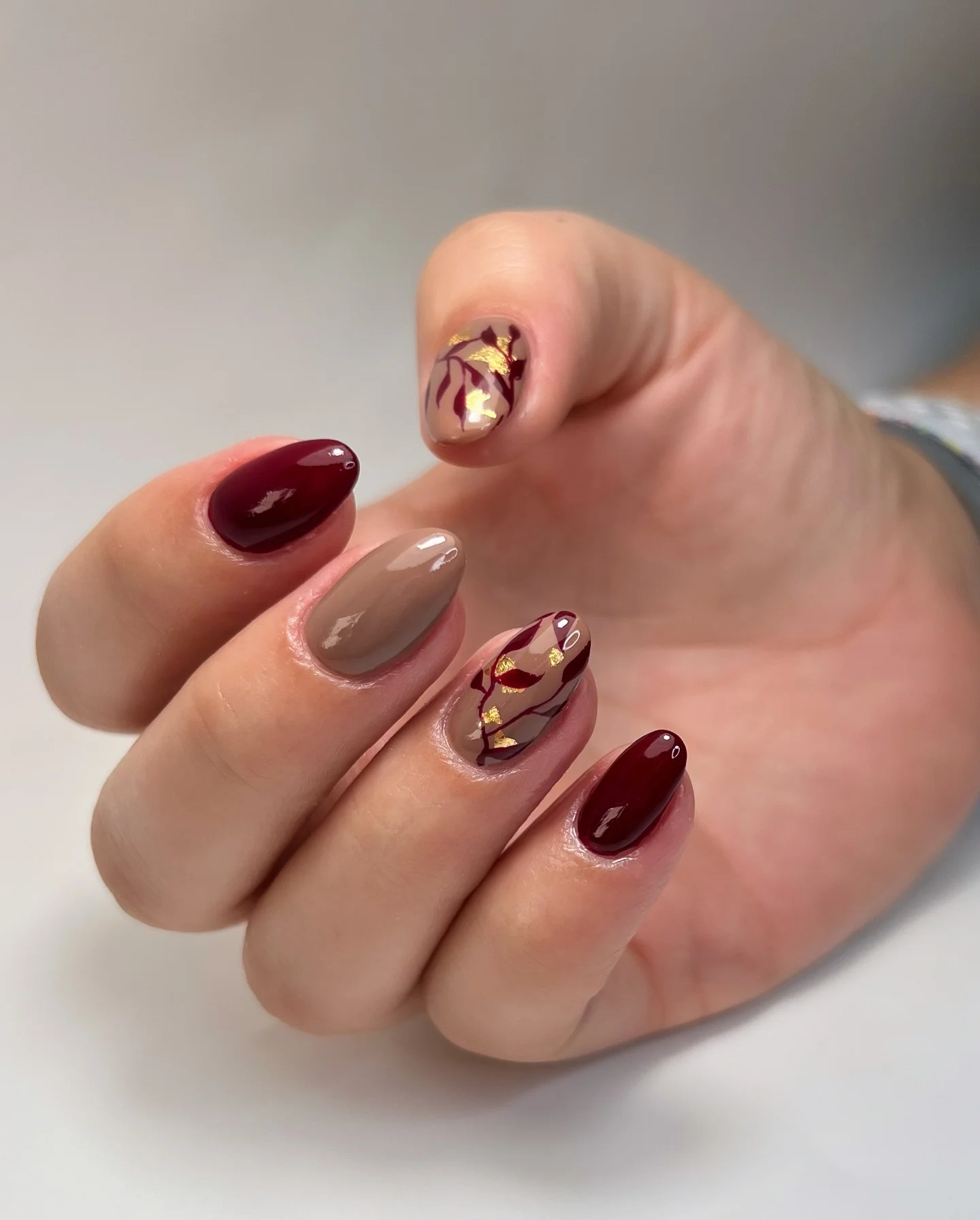 fall manicure 2026 Burgundy Marble Leaves With Gold Foil Accents