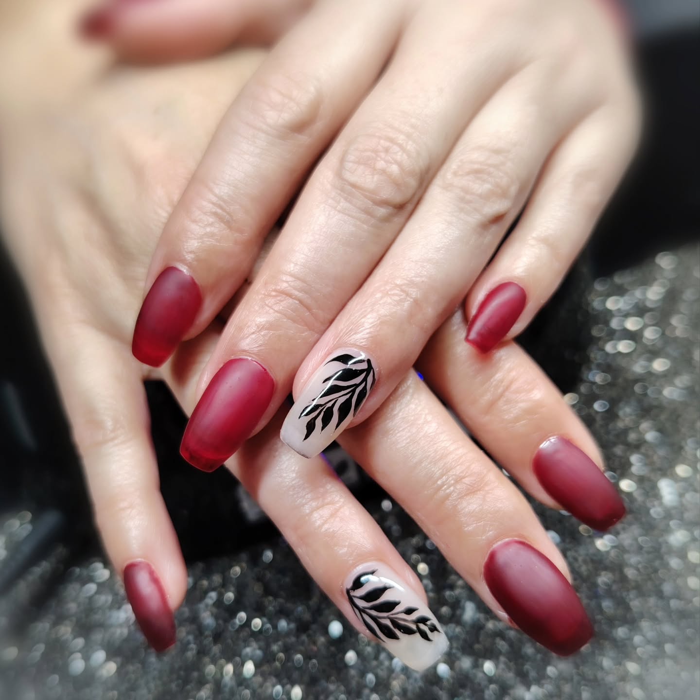 fall red nails 2026 Matte Burgundy Nails With Graphic Black Leaves