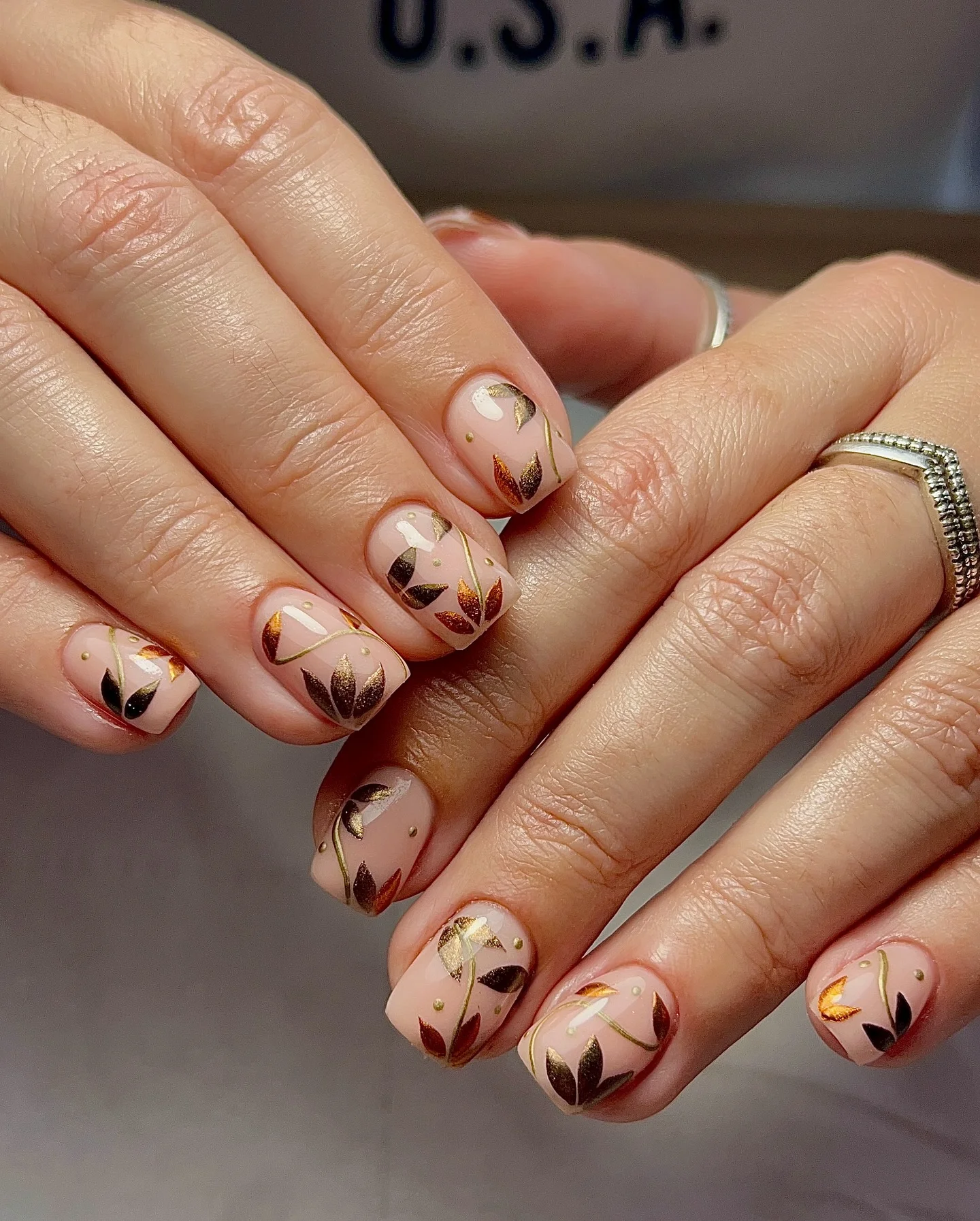 fall short nails 2026 Minimal Nude Nails With Metallic Autumn Leaf Art