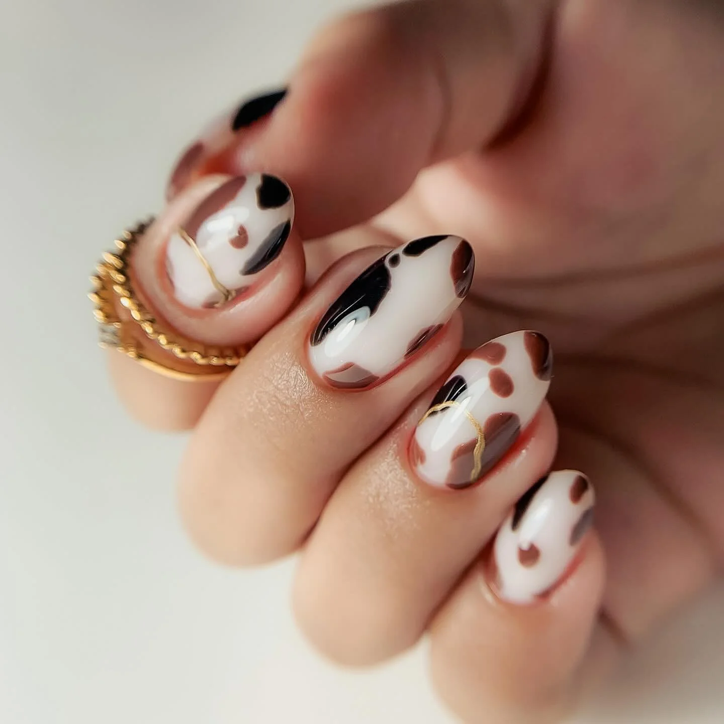 fall nail trends 2026 Abstract Cow Print With Fine Gold Details