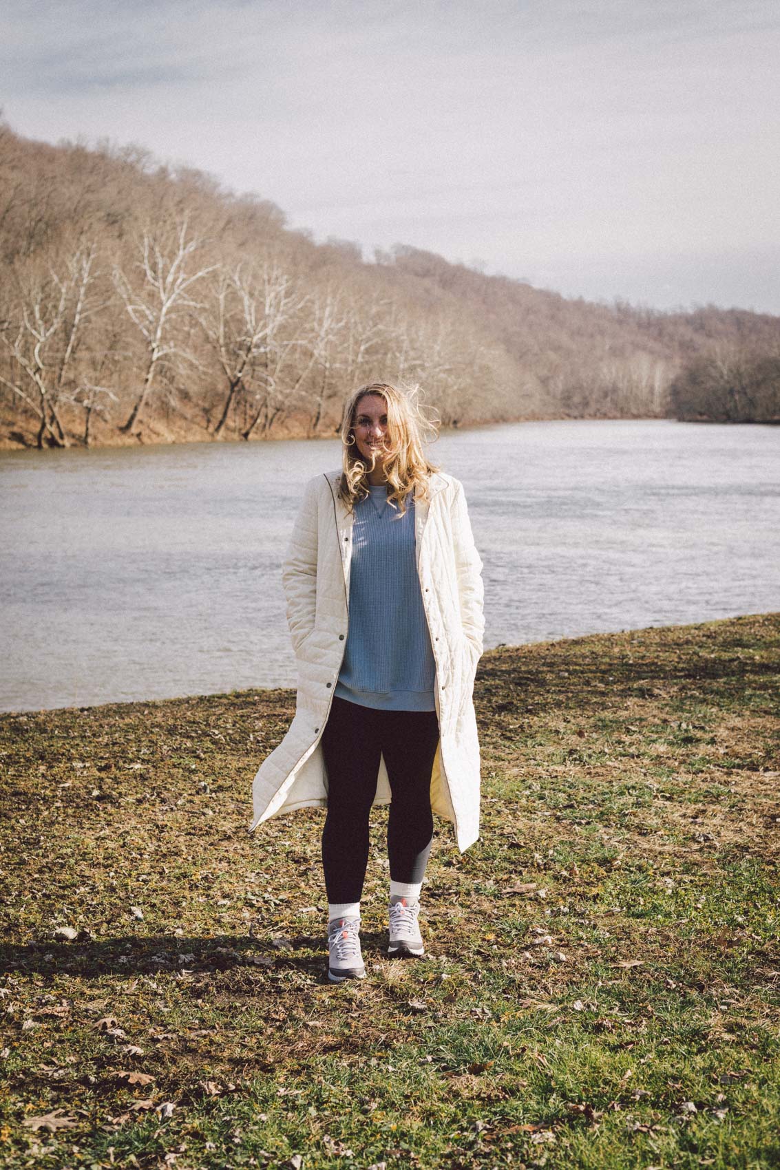 Crisp White Puffer with Blue Sweater and Grey Sneakers — Long Puffer Coat Outfits