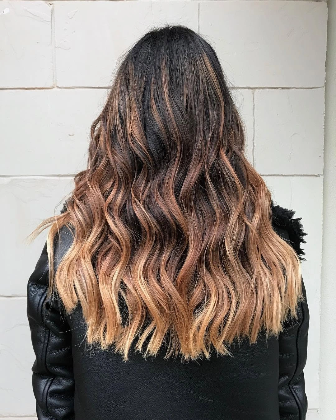 Long dark brunette waves transitioning into warm caramel blonde ends