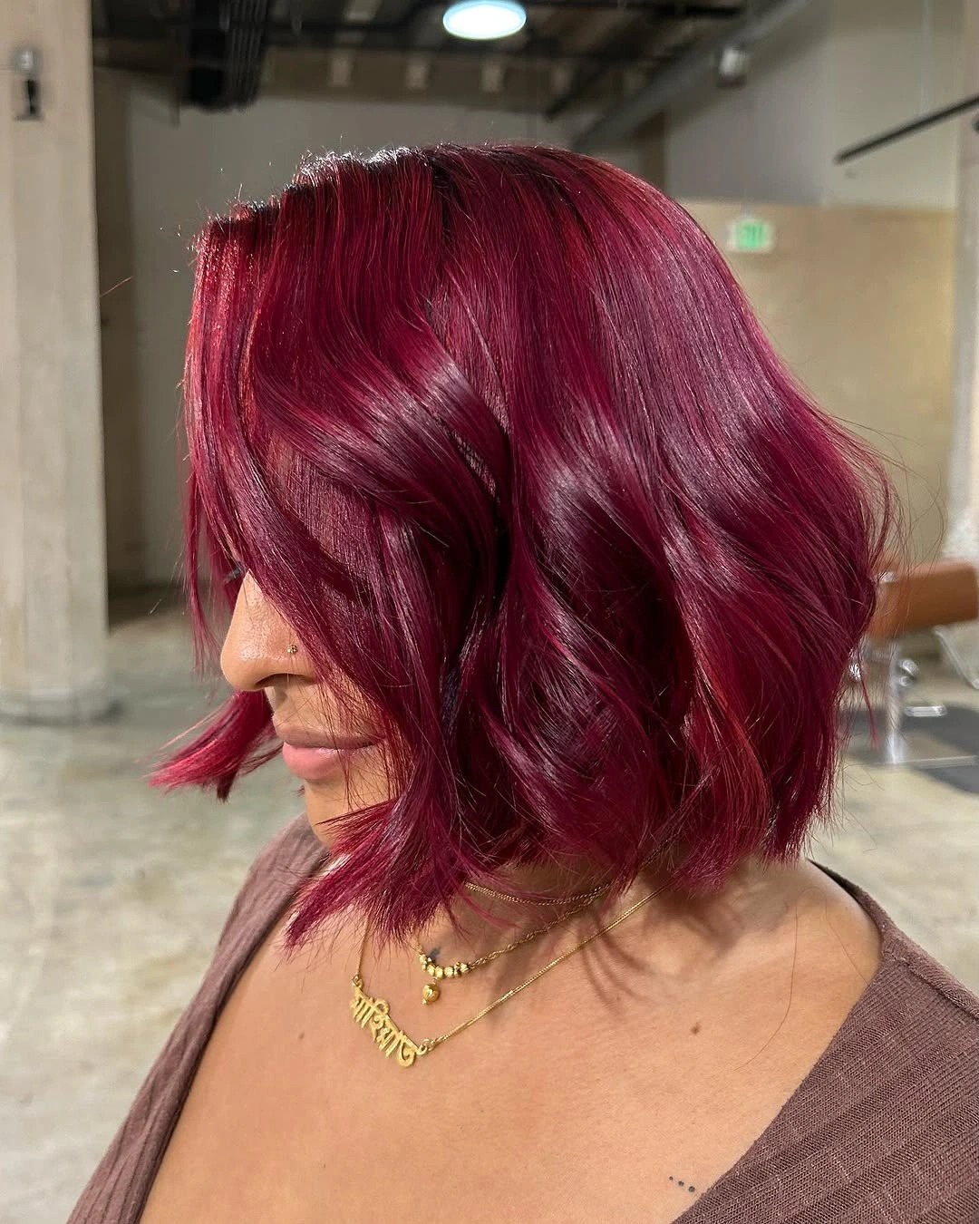 Short wavy garnet red bob with side swept layers and crimson highlights