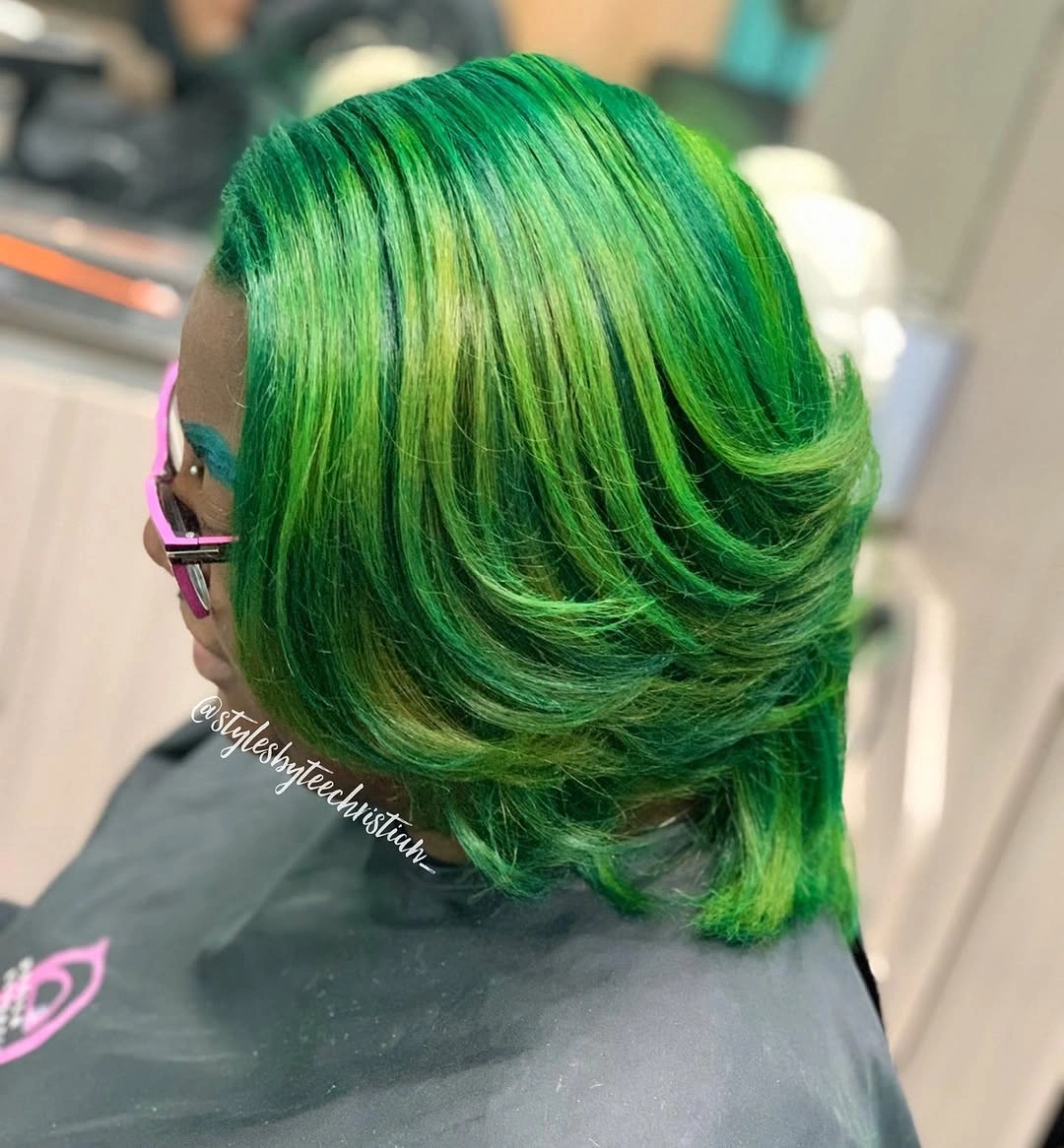 Vivid emerald green hair with lime highlights and swept back layers