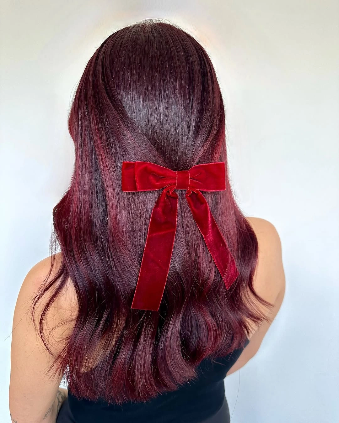 Long burgundy hair with soft waves and a red ribbon bow