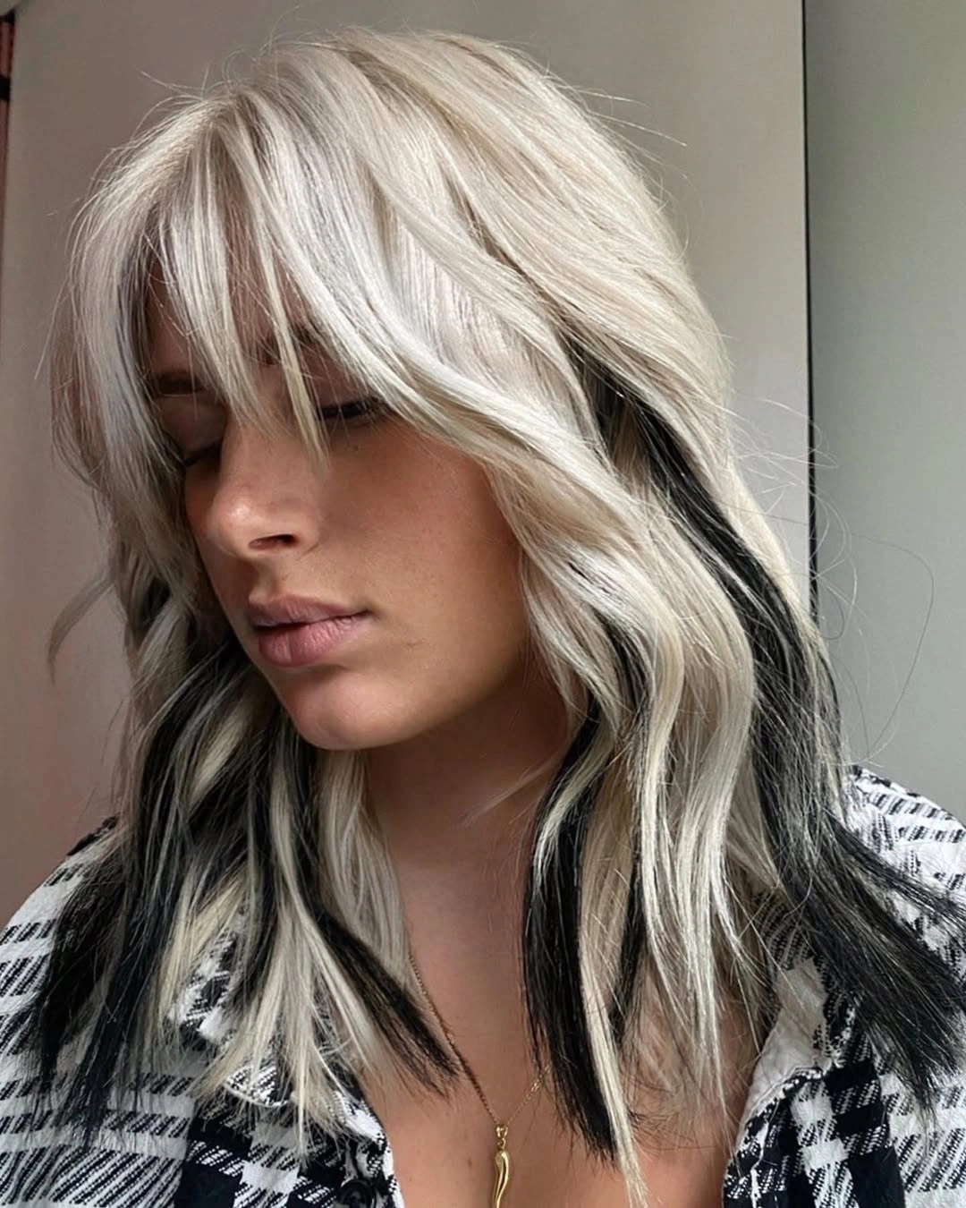 Short icy blonde wavy hair with black side sections and bangs