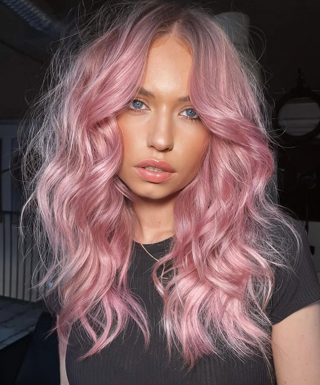 Medium length pastel pink hair with center parted waves and rosy highlights