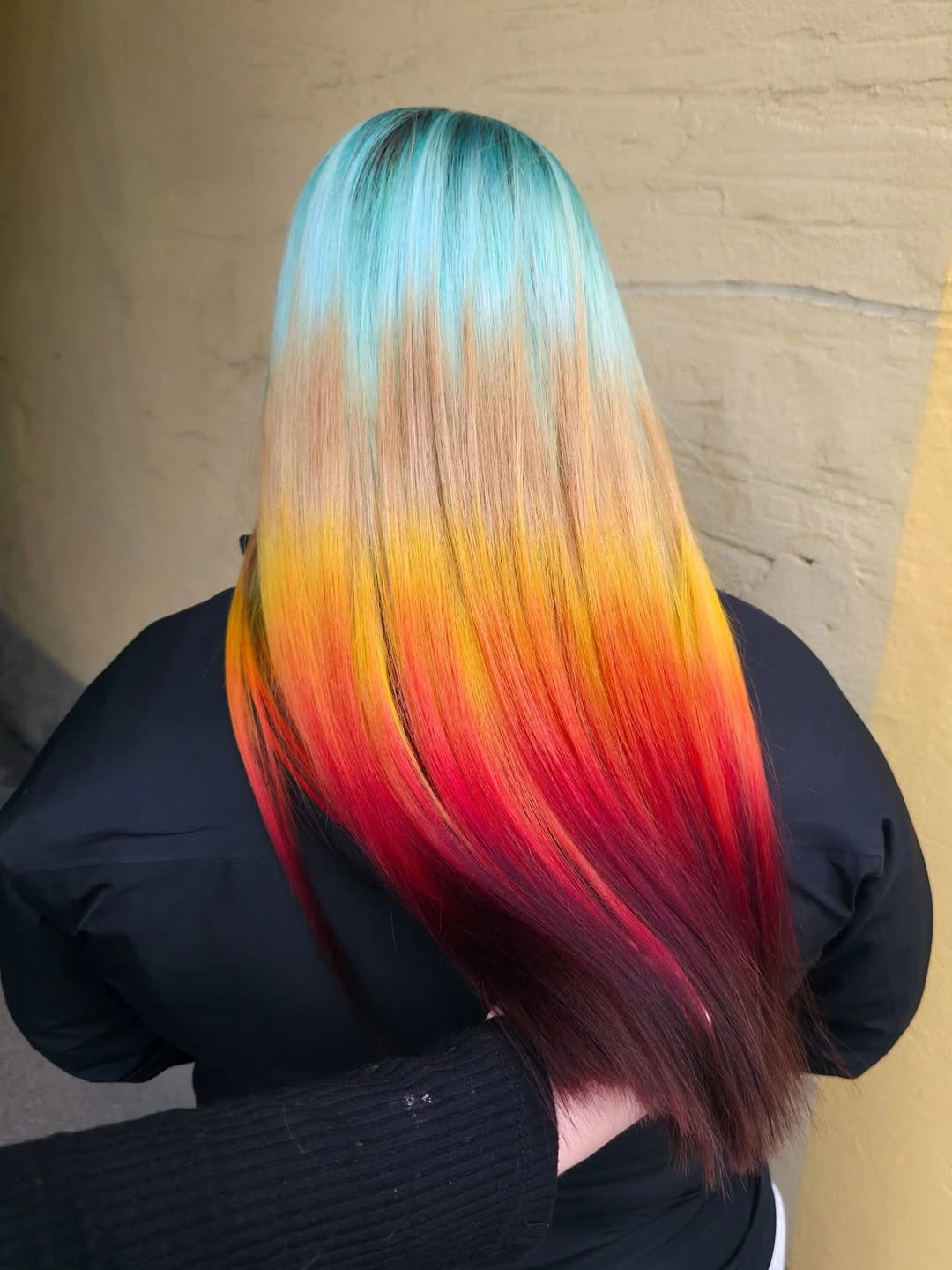 Long straight hair transitioning from turquoise through yellow orange red and burgundy