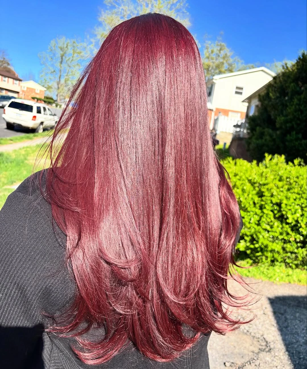 Long rose burgundy hair with glossy pink reflections and feathered layers