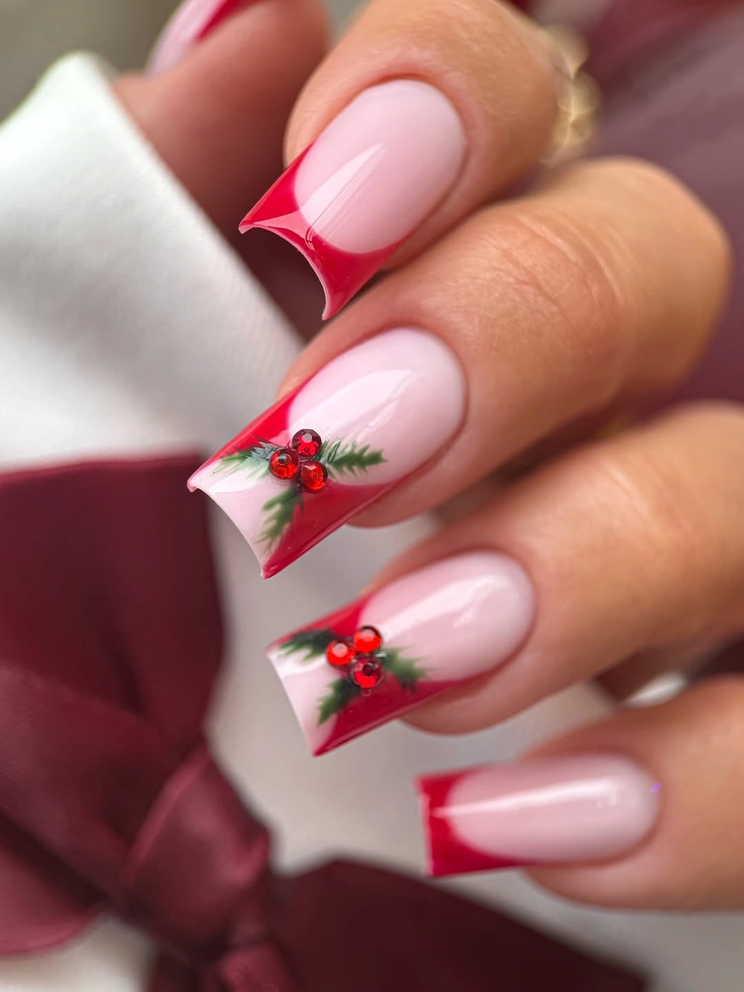 Long pink nails with cherry red tips green leaves and red berries