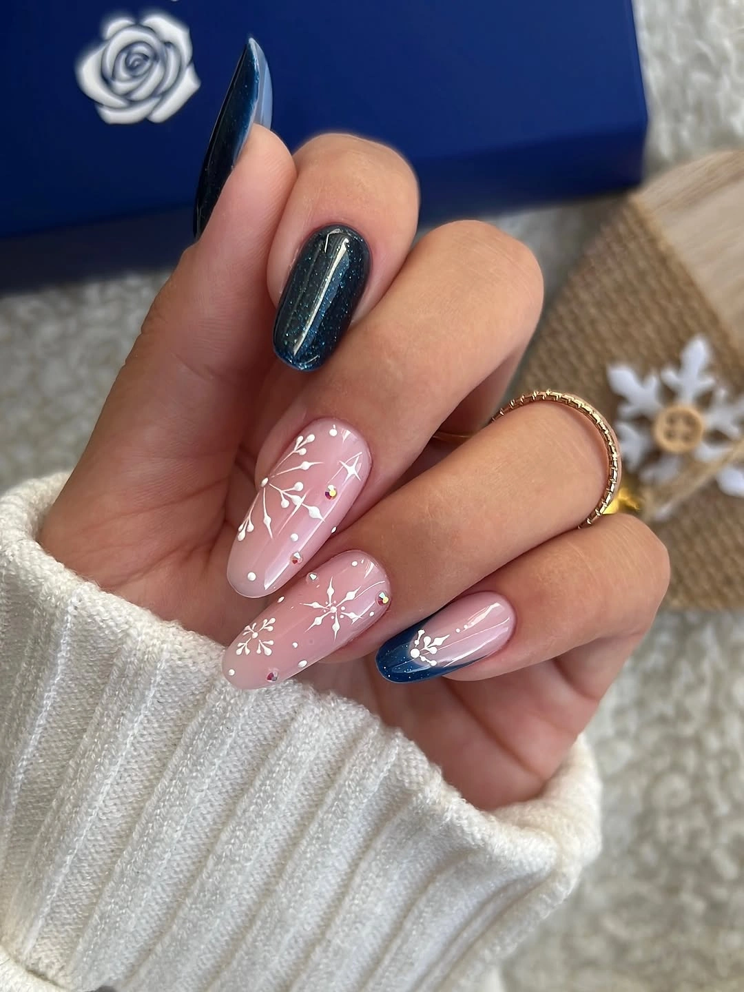 Long almond nails in navy blue and blush pink with white snowflakes