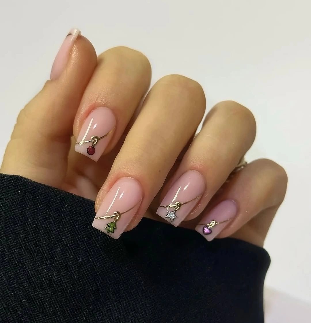 Blush pink almond nails with fine gold lines and colorful miniature charms