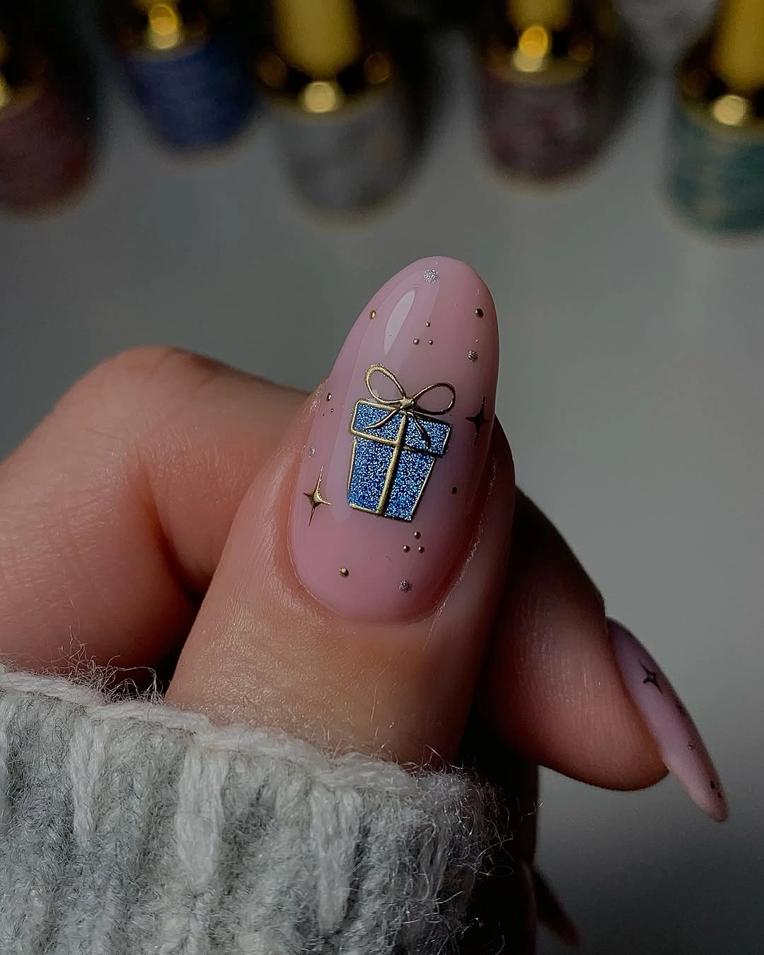 Long almond shaped dusty pink nail with blue gift box and gold bow