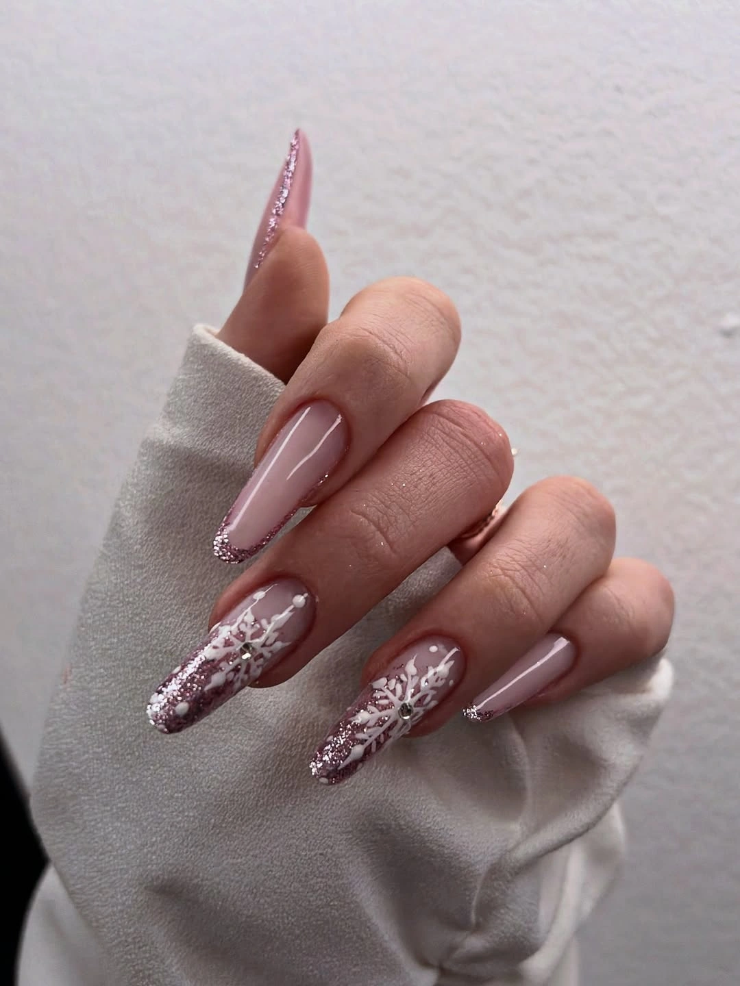 Long blush pink nails with silver glitter and white snowflakes