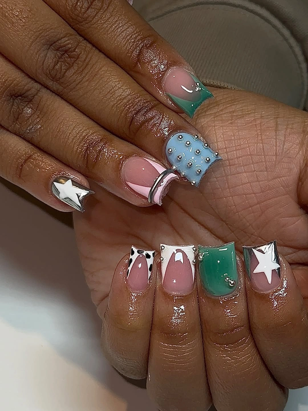 Long square nails with green blue pink white stars and decorative dots