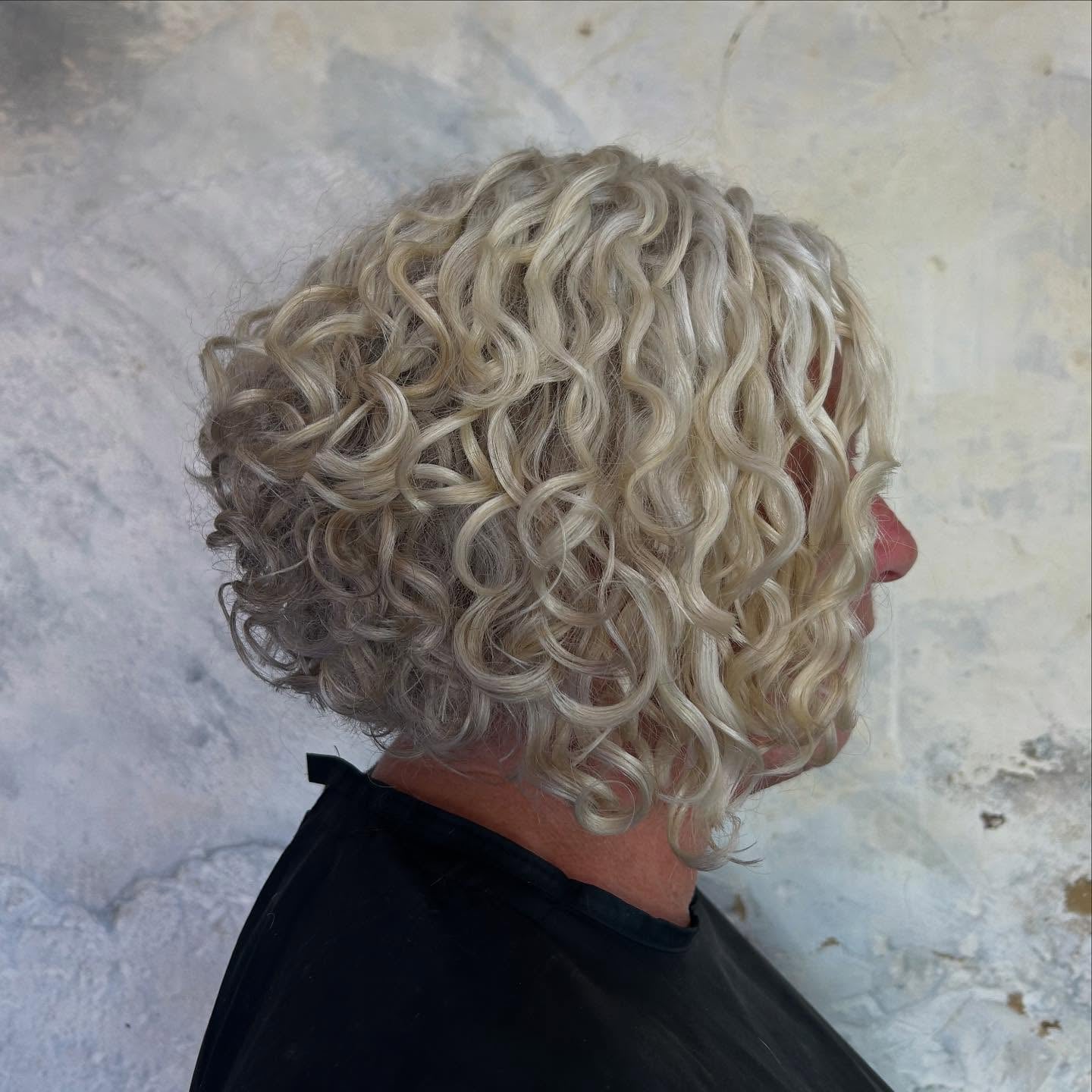 Platinum Blonde Stacked Bob With Tight Curls